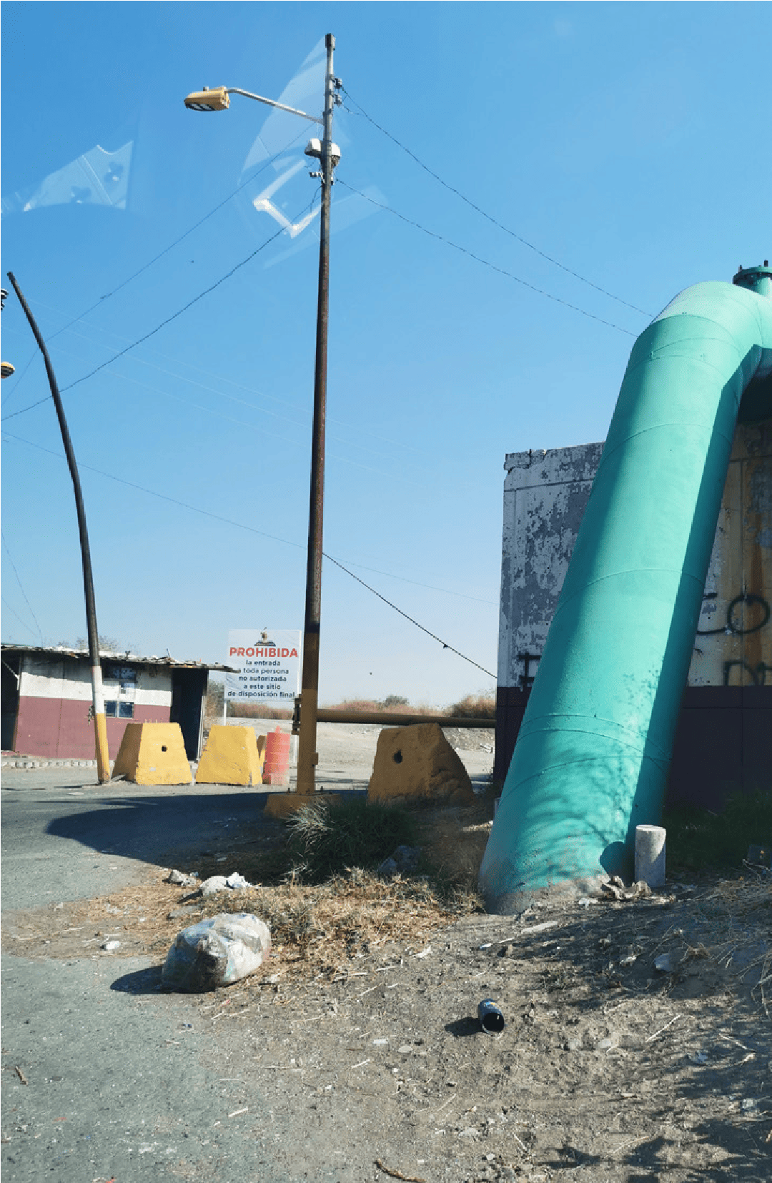The &ldquo;Prohibida&rdquo; sign indicates that the entrance is closed to outsiders; it is partially hidden by the guard shelter and the lampposts that mark the entrance to the landfill. The framing is wide, it shows no human presence, only the infrastructures that control passage: concrete bollards, a rising barrier, a guard shelter, a sign that states the rule of access: be an authorized person: but how? It does not say. The waste soundscape can be heard but not seen. The entrance to Neza 3 materializes the care ecotone as a zone of power: a physical boundary where implicit rules are tacitly negotiated.