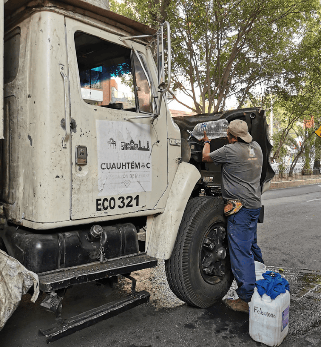 The engine overheated again; it is old and there is no money to repair it. So the collectors adapt and go into the street to fetch water to cool it down. This collective emergency gesture reveals how material care keeps the working tool alive. Without it, the entire chain stops: no truck, no collection, and therefore no income.