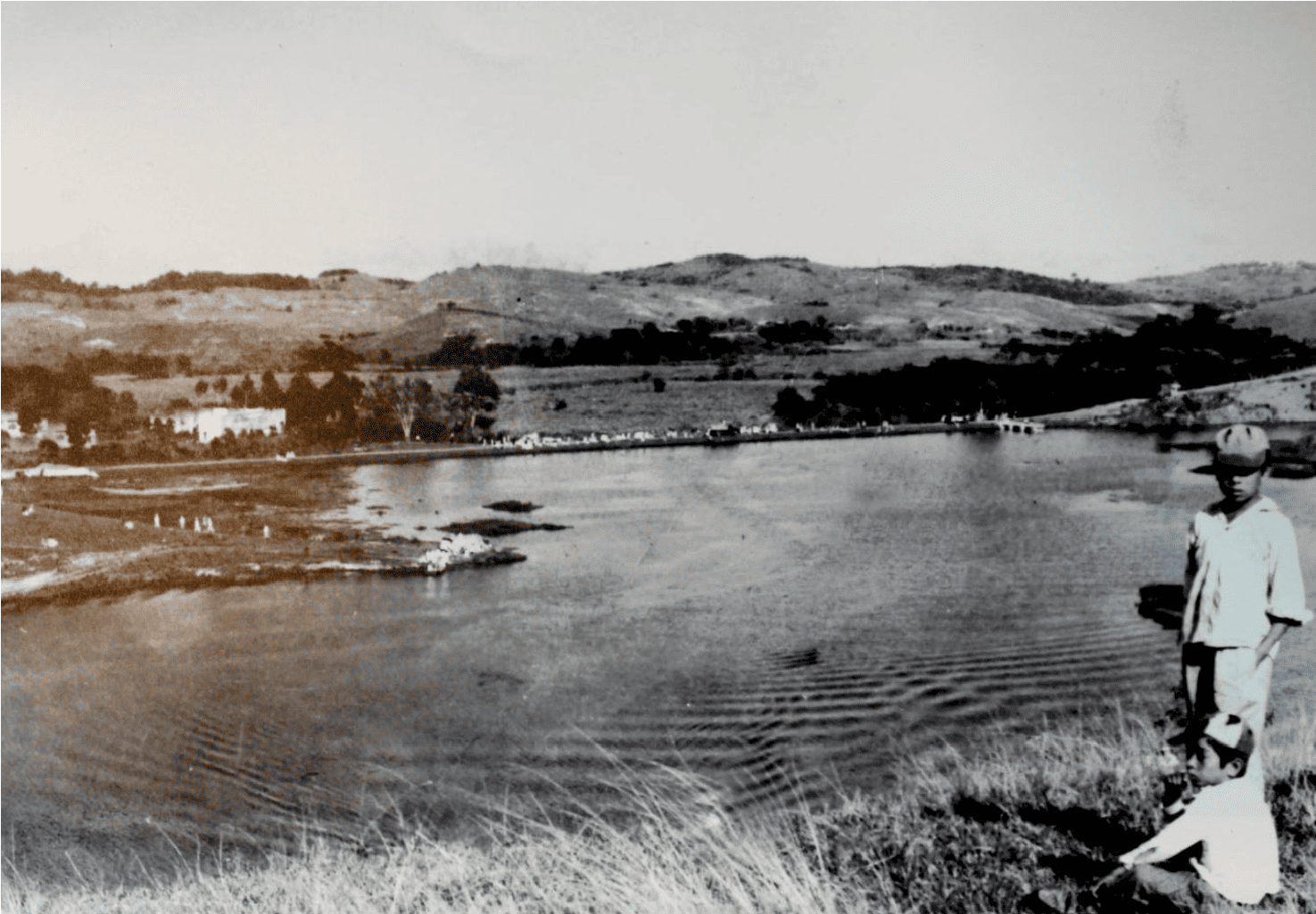 Fotografía histórica de la laguna del Castillo. Paisaje de la laguna del Castillo en los años sesenta del siglo pasado. Hacia el fondo se ve una calle recta que se hizo como muro de contención, y en su extremo derecho se vislumbra el muelle o «trampolín». La construcción a la izquierda corresponde a la casa original de la hacienda de La Palma. Fuente: José Isidro Caballero.