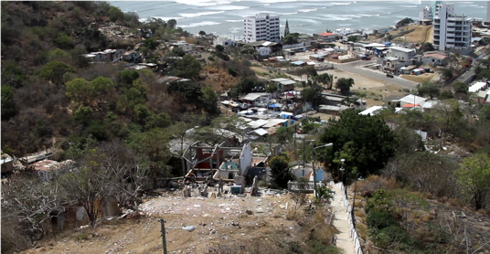 Figura 8. Vista panor&aacute;mica del barrio San Roque con casas derrumbadas y albergue al fondo, 2016.